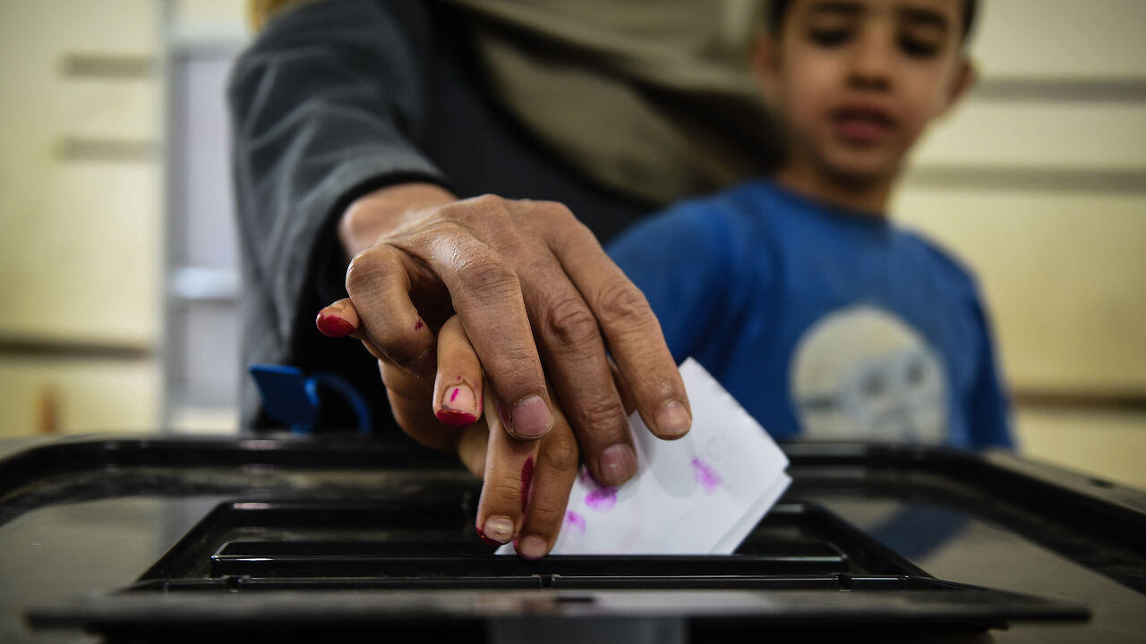 1138753585 An man Egyptian casts his ballot with a child at a polling station during the third day of a referendum on constitutional amendments, at a school in shamma village in the northern Nile delta province of Menoufia, on April 22, 2019. (Photo by Mohamed el-Shahed / AFP) (Photo credit should read MOHAMED EL-SHAHED/AFP/Getty Images)