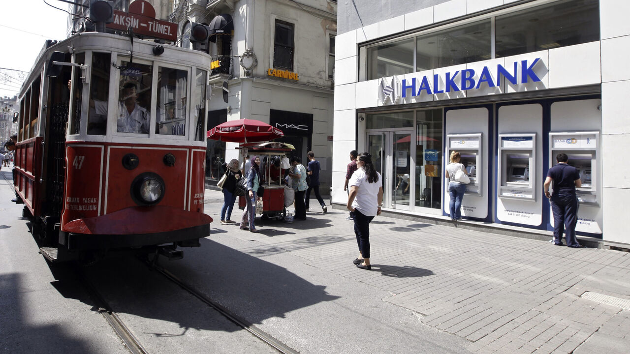 HALKBANK-CACANSKA/ Customers use automated teller machines at a branch of Halkbank as a tram drives by in Istanbul August 15, 2014. Turkey's state-run lender Halkbank said on Friday it has offer to buy a 76.76 percent stake in Serbian lender Cacanska Banka for an undisclosed sum. Halkbank offered no further details on the potential acquisition in a statement to the Istanbul stock exchange. REUTERS/Osman Orsal (TURKEY - Tags: BUSINESS) - GM1EA8F1N2P01