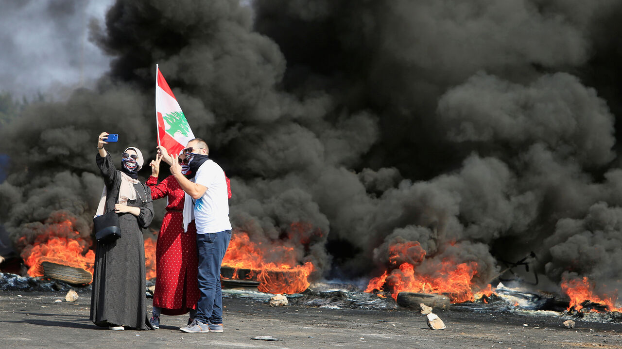LEBANON-ECONOMY/PROTESTS Demonstrators take a selfie in front of burning tires during a protest targeting the government over an economic crisis, at Barja area blocking off a main road leading from southern Lebanon to Beirut, October 18, 2019. REUTERS/Ali Hashisho - RC1FB9E67800