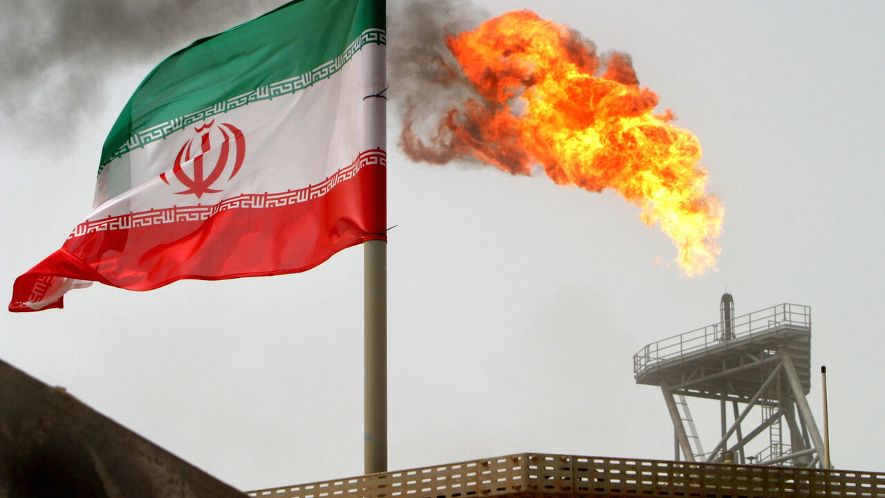 IRAN-OIL/EXPORTS A gas flare on an oil production platform in the Soroush oil fields is seen alongside an Iranian flag in the Gulf July 25, 2005. REUTERS/Raheb Homavandi/File Photo - S1BEUBPCZPAB
