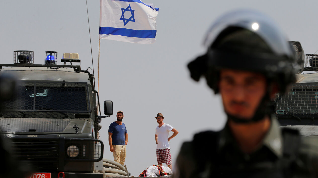 ISRAEL-PALESTINIANS/ Israeli settler look at Palestinian demonstrators during a protest against Jewish settlements, in Al-Sawaherh in the Israeli-occupied West Bank September 20, 2019. REUTERS/Mussa Qawasma - RC1C30A9A8D0