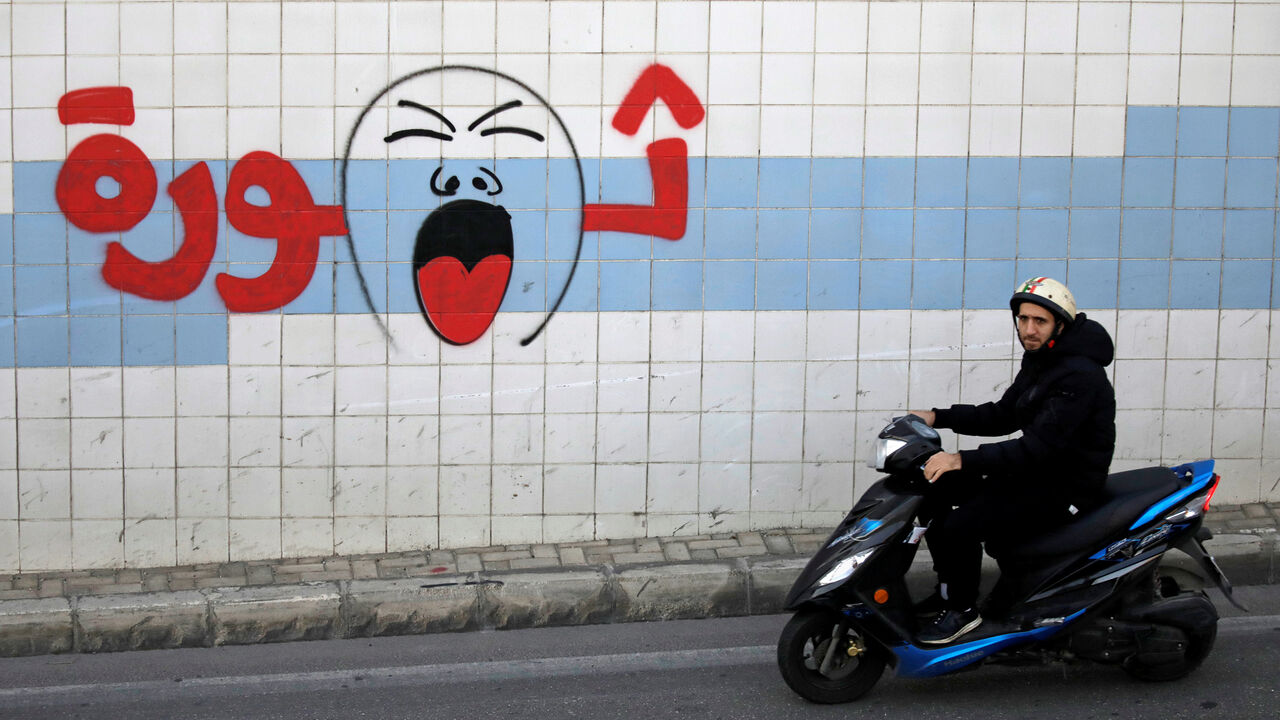 LEBANON-PROTESTS/ A man rides on a motorbike past graffiti which reads "Revolution", in Beirut, Lebanon, November 3, 2019. REUTERS/Andres Martinez Casares - RC1830CECF20