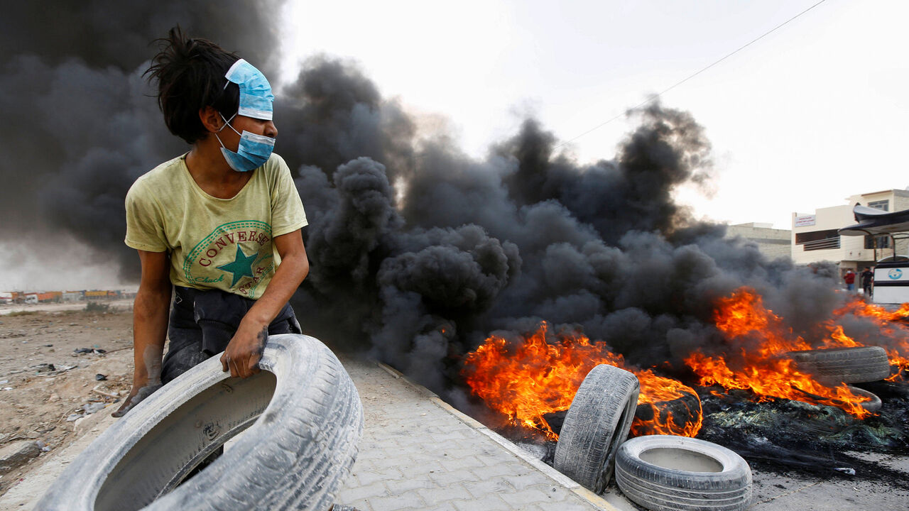 IRAQ-PROTESTS/ An Iraqi demonstrator burns tires during the ongoing anti-government protests in Najaf, Iraq November 18, 2019. REUTERS/Alaa al-Marjani - RC2ODD964QFI