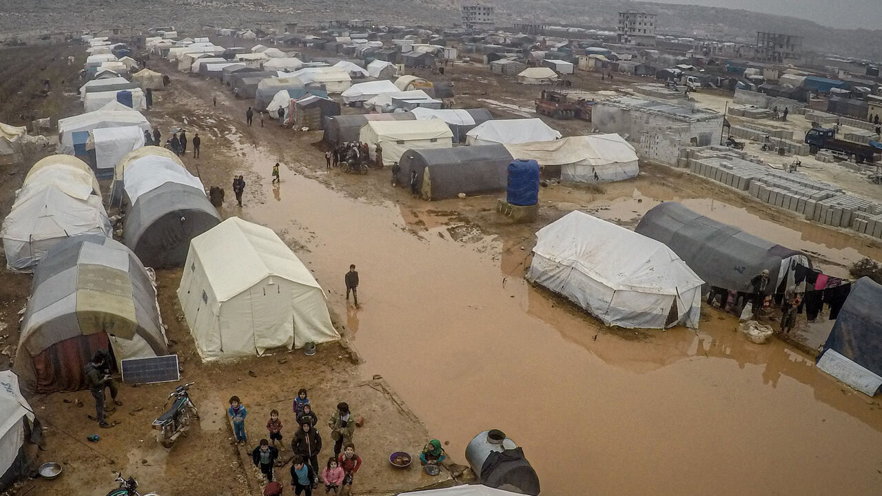 1188336682 IDLIB, SYRIA - DECEMBER 13: A drone photo shows an aerial view of the mud covered road and tents at a refugee camp, where Syrian refugees live, after heavy rain at winter season in northeastern Idlib, Syria on December 13, 2019. Syrian refugees, who have been living in the camp, face flooding, mud and puddles due to lack of infrastructure and sewerage network. (Photo by Muhammed Said/Anadolu Agency via Getty Images)