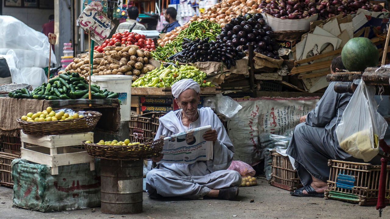 688075896 An Egyptian vendor reads the newspaper outside his fruit and vegetable stand in Egyptians in the Egyptian capital, Cairo, on May 15, 2017.
Ramadan is a time for daytime fasting and lavish evening feasts, but Egyptians are scaling back preparations for the Muslim holy month this year after austerity measures fuelled decades-high inflation. / AFP PHOTO / KHALED DESOUKI (Photo credit should read KHALED DESOUKI/AFP via Getty Images)