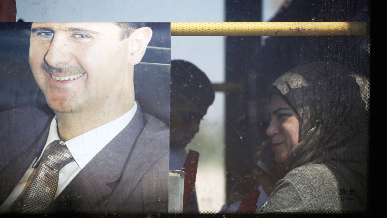 SYRIA-SECURITY/QUSAYR A returnee sits in a bus next to a picture of Syrian President Bashar al Assad in Qusayr, Syria July 7, 2019. REUTERS/Omar Sanadiki - RC16FEE06D50