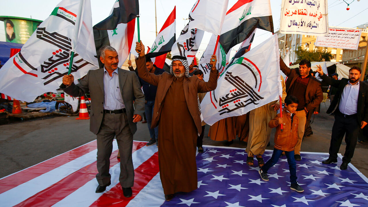 IRAQ-SECURITY/USA Iraqi people walk on a U.S. flag in a protest after an airstrike at the headquarters of Kataib Hezbollah militia group in Qaim, in the holy city of Najaf, Iraq December 30, 2019. REUTERS/Alaa al-Marjani - RC2Q5E9X7DV4