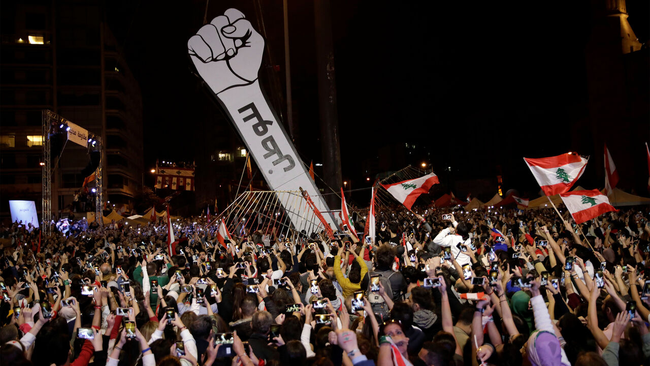 LEBANON-PROTESTS/ Protesters use their mobile phones as a structure representing a fist is erected to replace a previous one that was burnt at Martyrs' Square in Beirut, Lebanon November 22, 2019. REUTERS/Andres Martinez Casares - RC2JGD9MQQHD