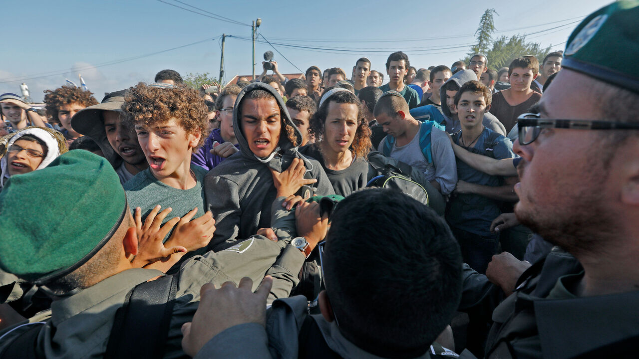 TOPSHOT - Israeli settlers scuffle with Israeli security forces at Netiv Haavot settlement, near Bethlehem, in the occupied West Bank on June 12, 2018. - Fifteen Israeli settler families are expected to evacuate their homes in this outpost after it was declared illegal by the Israeli High Court (Photo by Menahem KAHANA / AFP)        (Photo credit should read MENAHEM KAHANA/AFP via Getty Images)