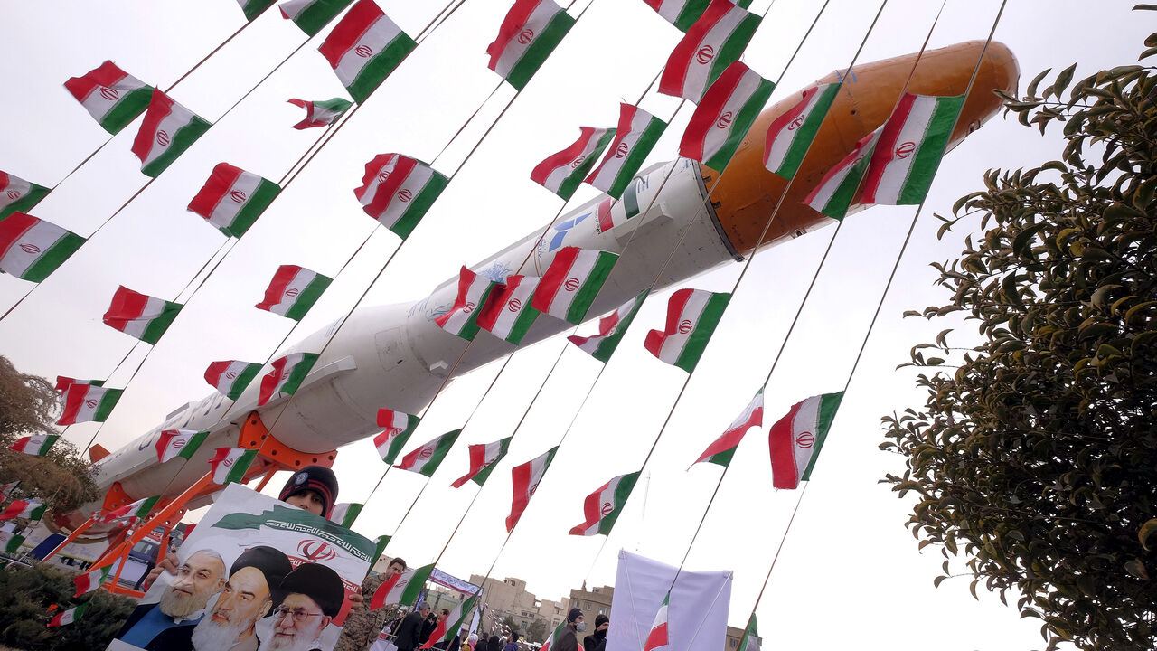 IRAN-ANNIVERSARY/ A boy holding a placard with pictures of (L-R) President Hassan Rouhani, the late founder of the Islamic Revolution Ayatollah Ruhollah Khomeini, and Iran's Supreme Leader Ayatollah Ali Khamenei, poses for camera in front of a model of Simorgh satellite-carrier rocket during a ceremony marking the 37th anniversary of the Islamic Revolution, in Tehran February 11, 2016. REUTERS/Raheb Homavandi/TIMAATTENTION EDITORS - THIS IMAGE WAS PROVIDED BY A THIRD PARTY. FOR EDITORIAL USE ONLY. - GF10000304511