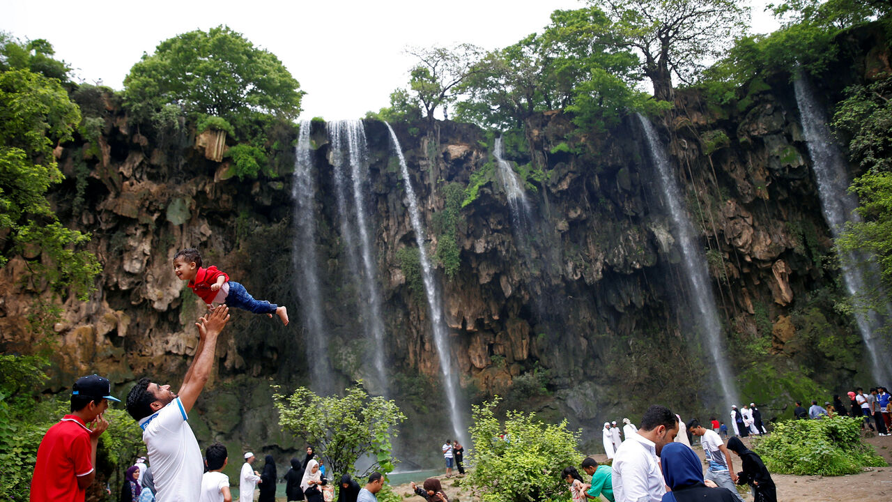 OMAN-TOURISM/ A tourist lifts up a boy as they visit waterfalls at Ayn Athum in Salalah, Dhofar province, Oman August 23, 2016. Picture taken August 23, 2016. REUTERS/Ahmed Jadallah - D1BETYFAUFAC