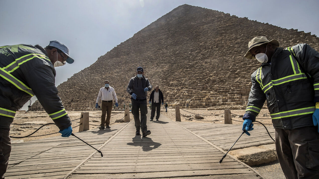 1208218503 TOPSHOT - Egyptian municipality workers disinfect the Giza pyramids necropolis on the southwestern outskirts of the Egyptian capital Cairo on March 25, 2020 as protective a measure against the spread of the coronavirus COVID-19. (Photo by Khaled DESOUKI / AFP) (Photo by KHALED DESOUKI/AFP via Getty Images)