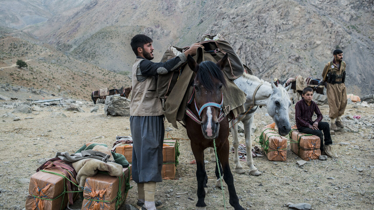 856013076 ZAGROS, IRAQ - JULY 27: A Kurdish-Iranian smuggler packs his horse in preparation to carry goods over the Iraq border into Iran on July 27, 2017 in the Zagros Mountains, northern Iraq. (Photo by Martyn Aim/Corbis via Getty Images)
