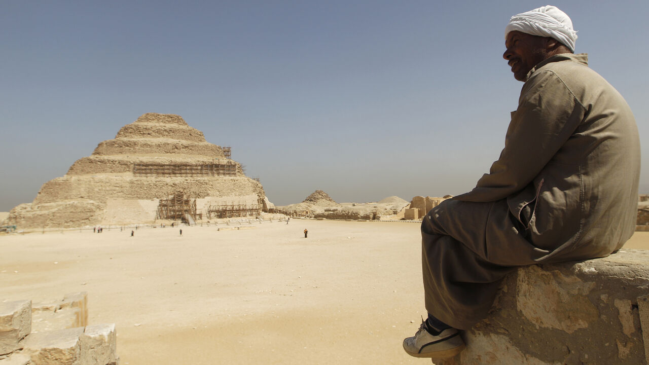 EGYPT-TOURISTS/ A guide sits on a stone as he looks at the Djoser's step pyramid in Saqqara, outside of Cairo March 5, 2011. Sites around the great pyramid at Giza, a Wonder of the Ancient World, the Sphinx and the cemetery at Sakkara have been nearly empty of tourists since a revolt started a month ago that ousted Hosni Mubarak and now Egypt wants visitors to return. REUTERS/Peter Andrews (EGYPT - Tags: CIVIL UNREST POLITICS TRAVEL SOCIETY) - GM1E7351JOK01