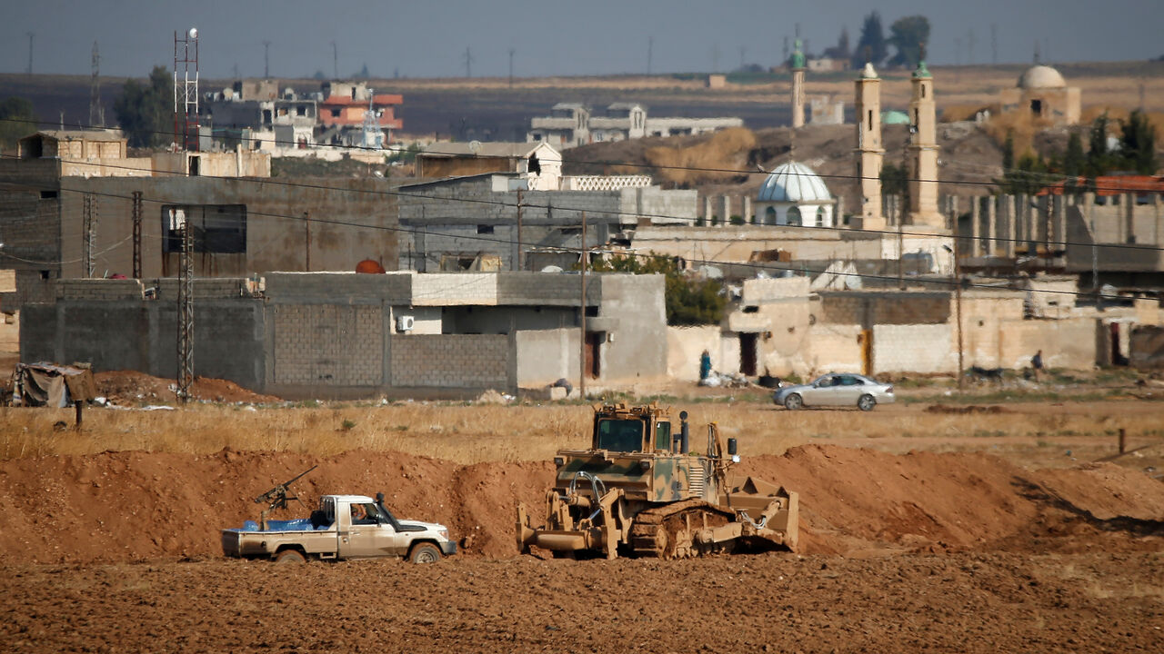 SYRIA-SECURITY/TURKEY A vehicle belonging to Turkey-backed Syrian rebel fighters is parked next to a Turkish military bulldozer in the Syrian town of Ras al Ain, as seen from the Turkish border town of Ceylanpinar, in Sanliurfa province, Turkey, October 30, 2019. REUTERS/Kemal Aslan - RC121F436090