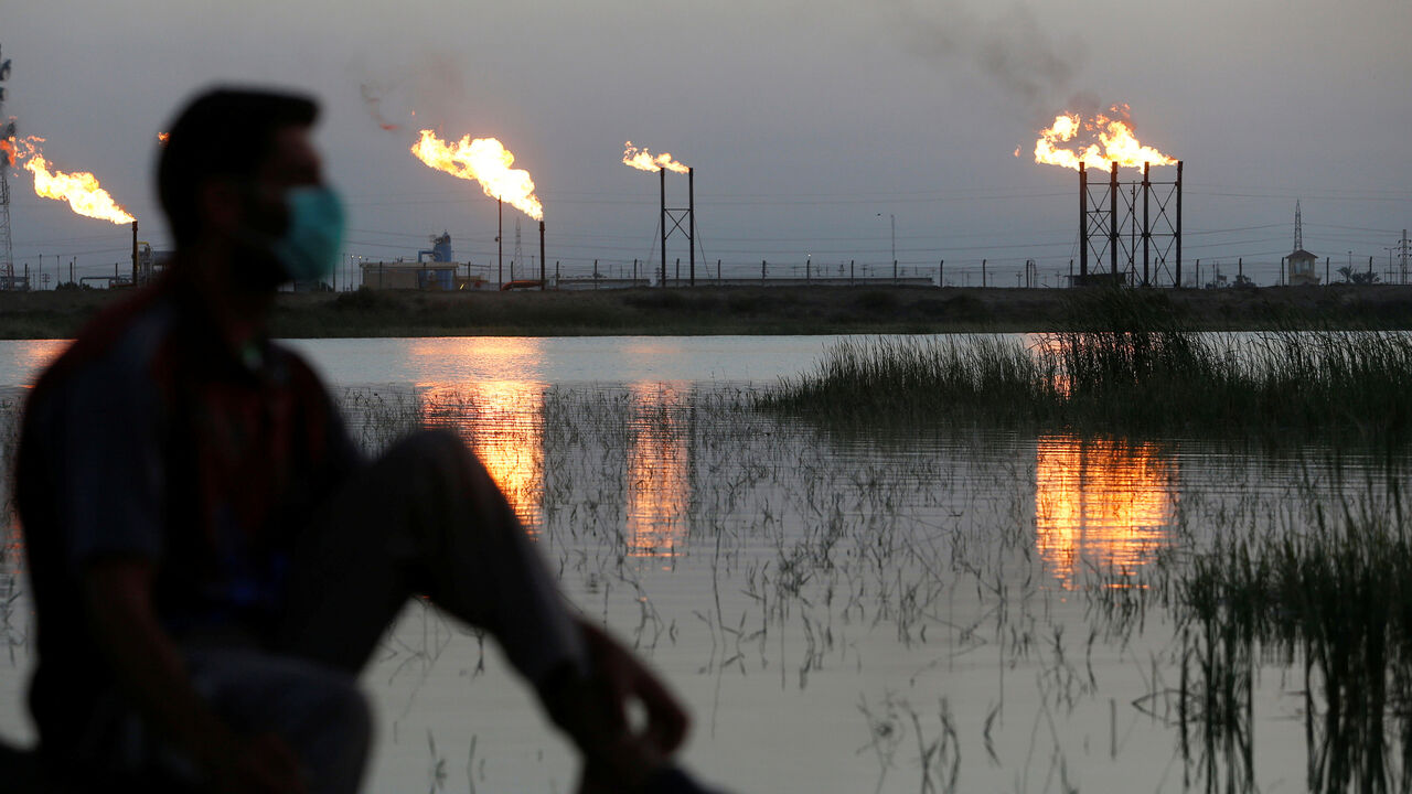 SAUDI ARAMCO-STOCKS/ Flames emerge from flare stacks at Nahr Bin Umar oil field, as a man is seen wearing a protective face mask, following the outbreak of the coronavirus, north of Basra, Iraq March 9, 2020. REUTERS/Essam Al-Sudani - RC2IGF9A1IYO