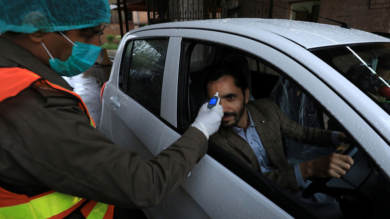 HEALTH-CORONAVIRUS/PAKISTAN A rescue worker wears protective hand gloves as he checks a man?s temperature amid coronavirus fears, at the entrance of the government office building in Peshawar, Pakistan March 12, 2020. REUTERS/Fayaz Aziz - RC26IF9CRNEA