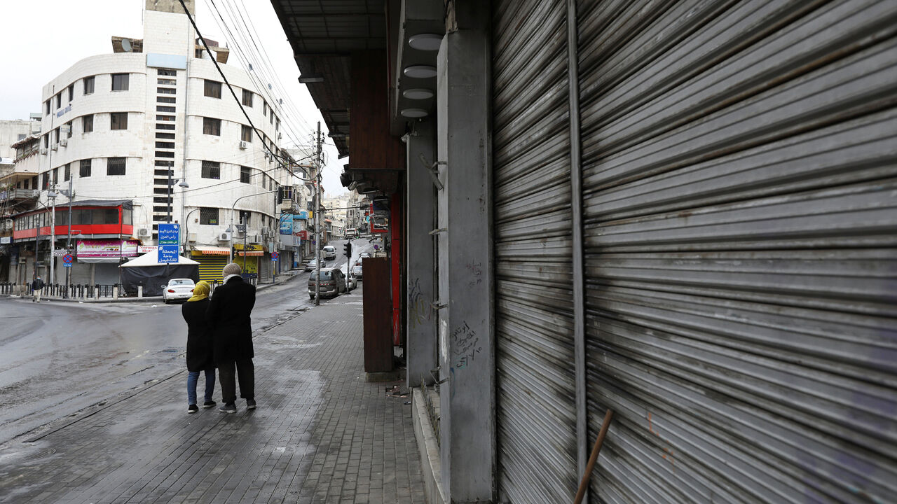 HEALTH-CORONAVIRUS/JORDAN People walk next to closed shops as the country takes measures to fight the spread of the coronavirus disease (COVID-19), in Amman, Jordan, March 18, 2020. REUTERS/Muhammad Hamed - RC2FMF9P4H3O