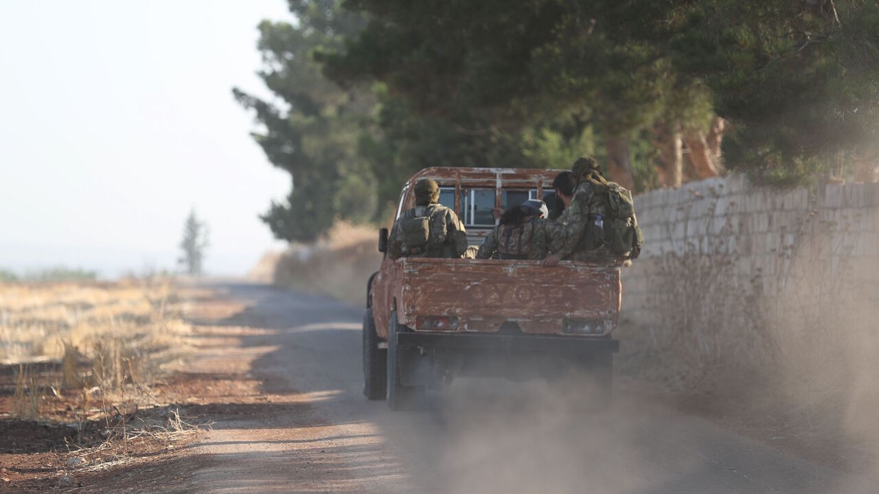1155035630 Fighters from the former al-Qaeda Syrian affiliate Hayat Tahrir al-Sham (HTS) drive through the village of Hamameyat on the border between Hama and Idlib provinces on July 11, 2019. - Regime and jihadist-led forces were locked in clashes on the edge of the opposition bastion in northwest Syria on July 11, after a jihadist-led advance that killed dozens of fighters overnight. Russian and regime aircraft have ramped up their deadly bombardment of the Idlib region -- administered by HTS, and home to some three