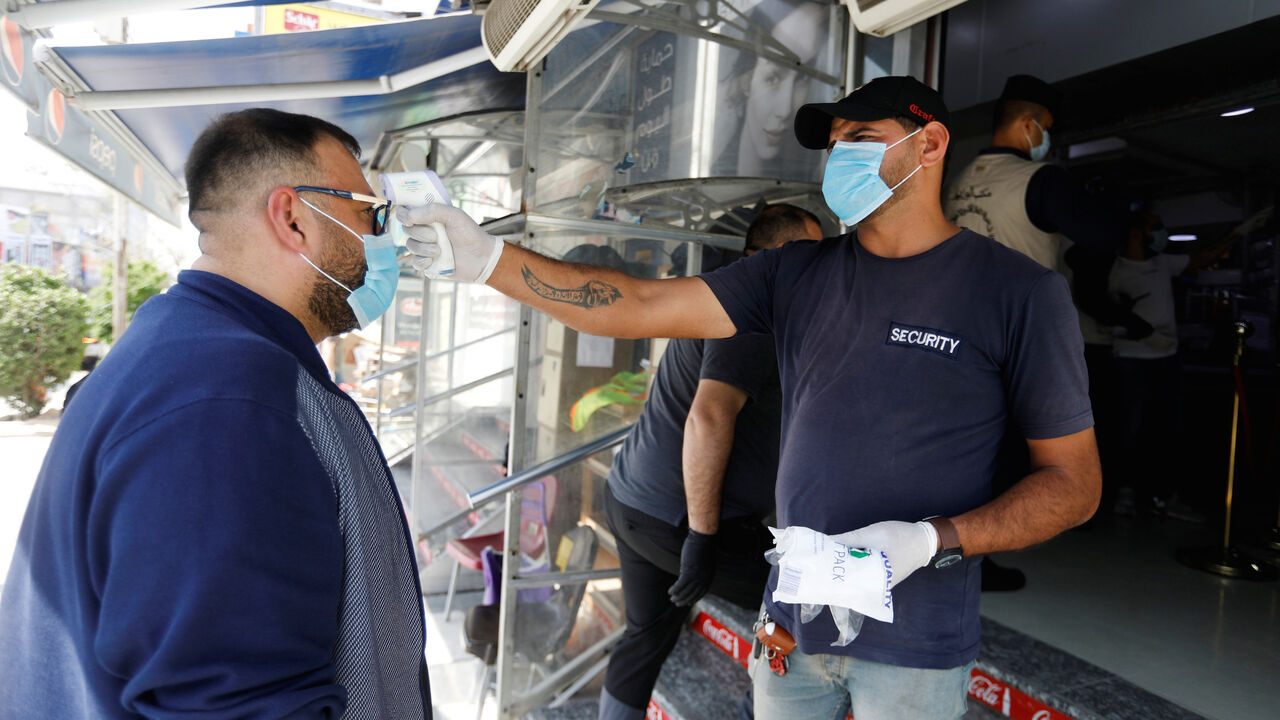 HEALTH-CORONAVIRUS/IRAQ-SHOPPING A security man checks the temperature of a customer, as he enters the supermarket before curfew , following the outbreak of coronavirus, in Baghdad, Iraq March 17, 2020. REUTERS/Khalid al-Mousily - RC2RLF917B9G