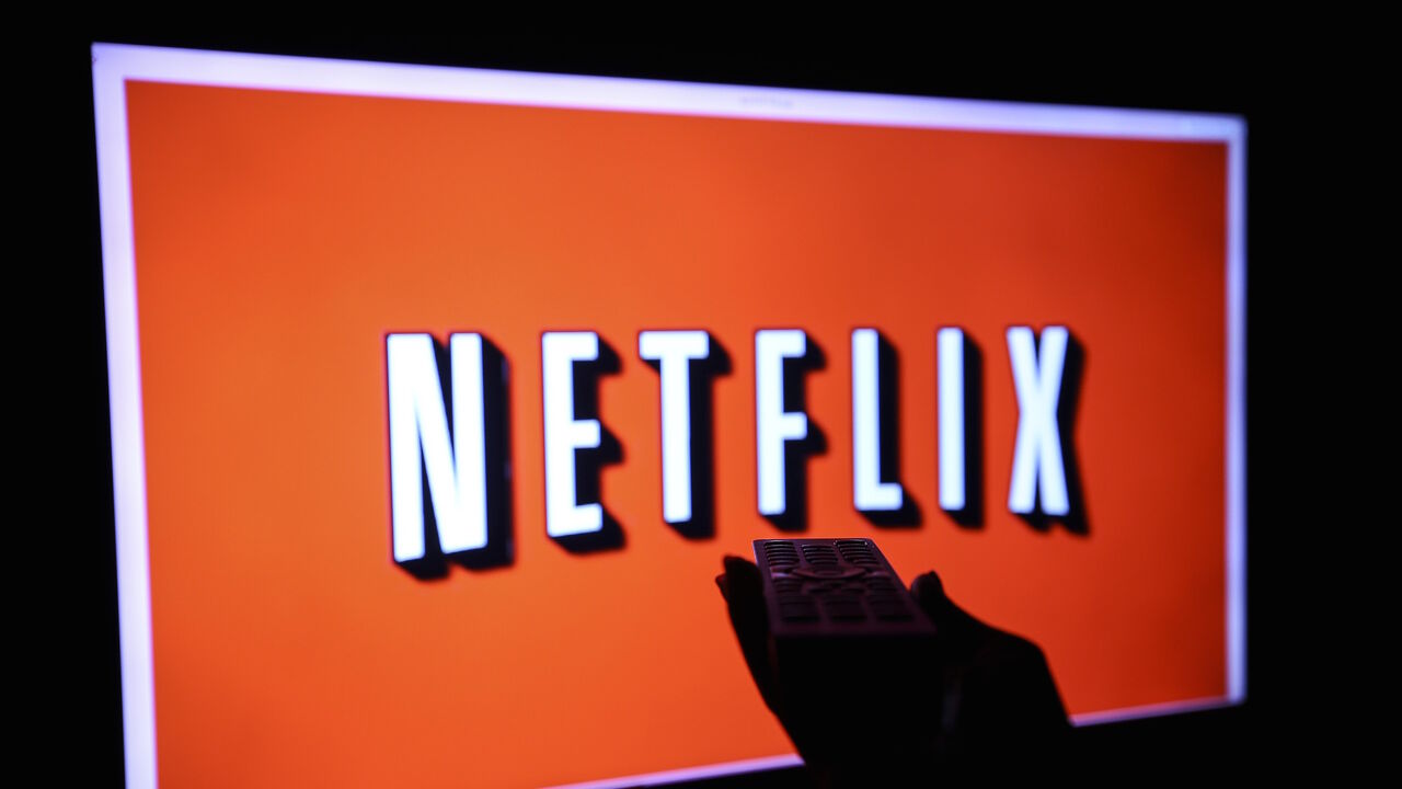 1065620226 ANKARA, TURKEY - NOVEMBER 27: A woman holds a remote control in front a TV screen displaying Netflix logo in Ankara, Turkey on November 27, 2018. (Photo by Ercin Top/Anadolu Agency/Getty Images)