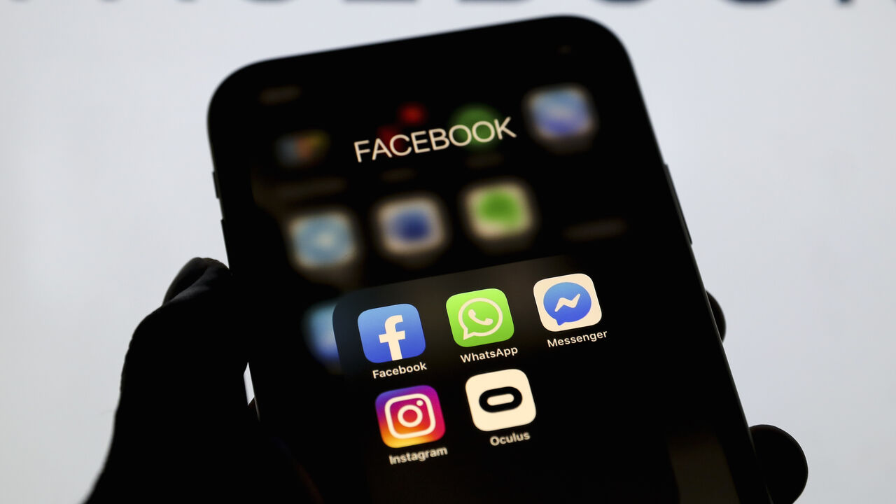 1211698396 ANKARA, TURKEY - MAY 4: In this illustration photo logos of social media applications WhatsApp, Instagram, Messenger, Oculus are seen on a mobile phone as Facebook logo is seen behind on a screen, in Ankara, Turkey on May 4, 2020. (Photo by Hakan Nural/Anadolu Agency via Getty Images)