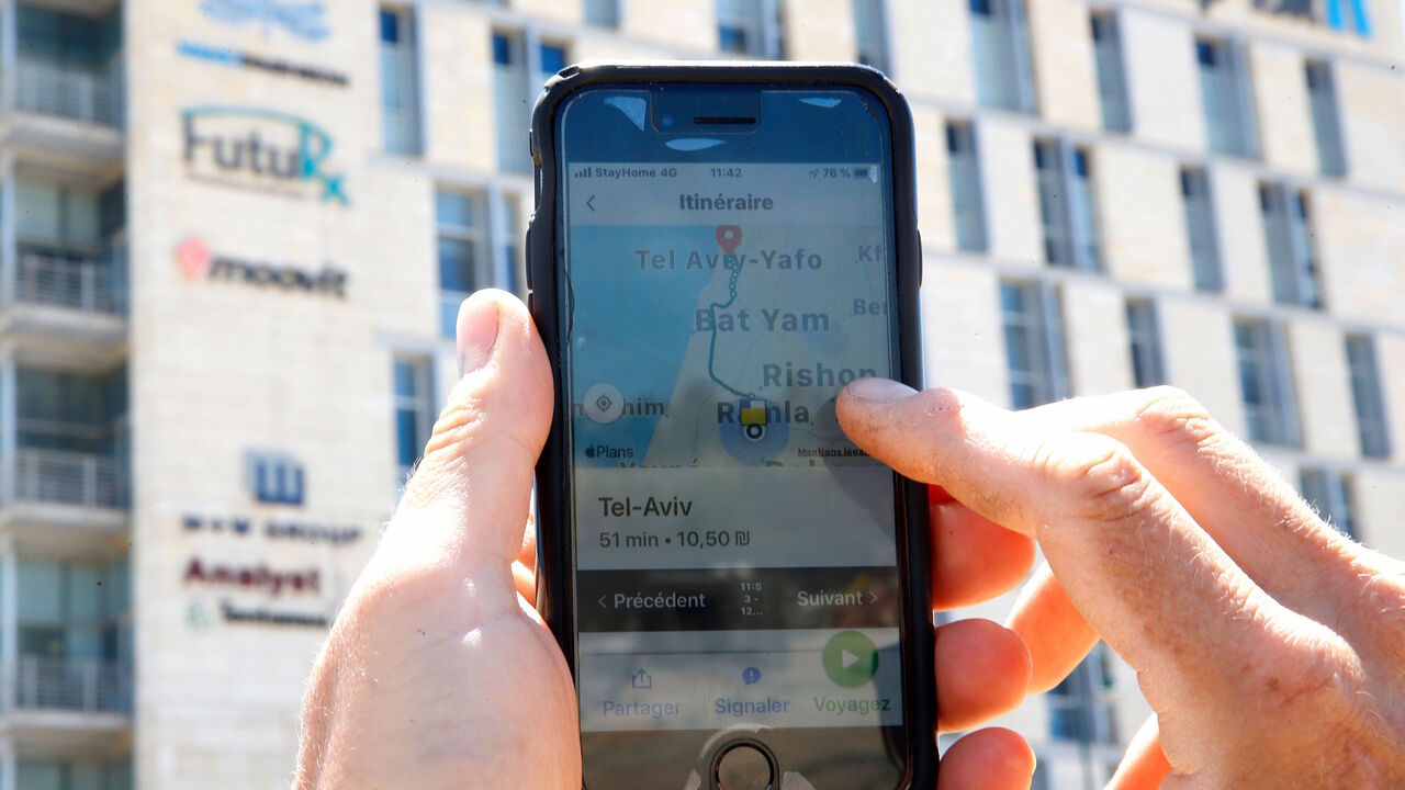1211709855 A man checks on his phone the Moovit mobile transport application in the central Israeli city of Ness Ziona on May 4, 2020. (Photo by JACK GUEZ / AFP) (Photo by JACK GUEZ/AFP via Getty Images)