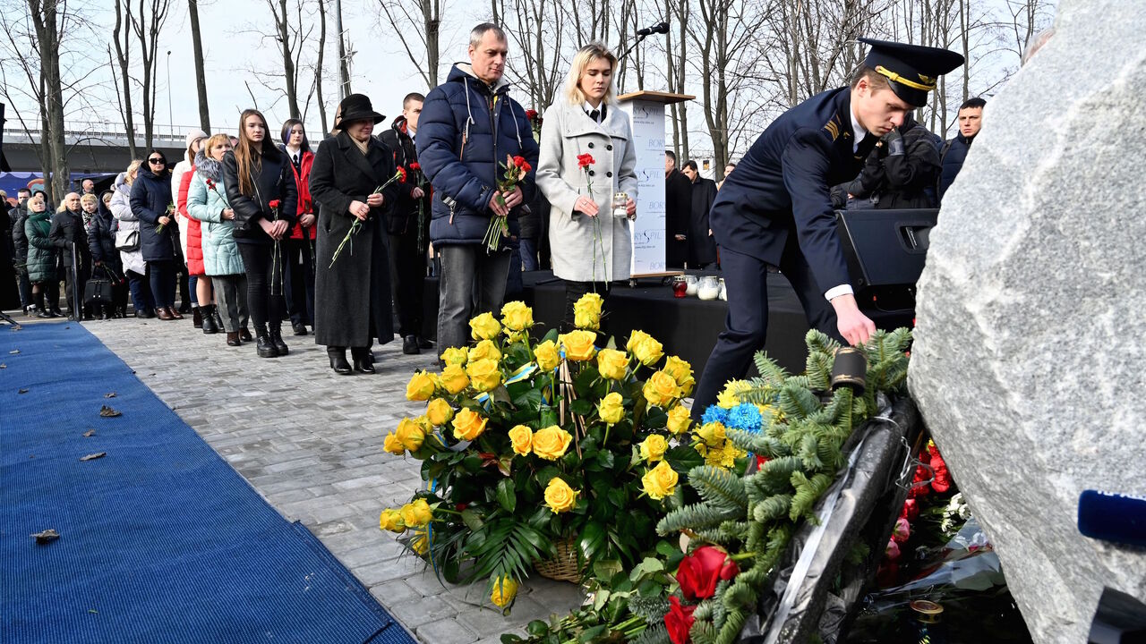 1201476602 Relatives and colleagues of the 11 Ukrainians who died in a plane mistakenly shot down by Iran in January, lay flowers during a ceremony unveiling a memorial stone at the site of the future monument at the Boryspil International airport outside Kiev on February 17, 2020. (Photo by Sergei SUPINSKY / AFP) (Photo by SERGEI SUPINSKY/AFP via Getty Images)
