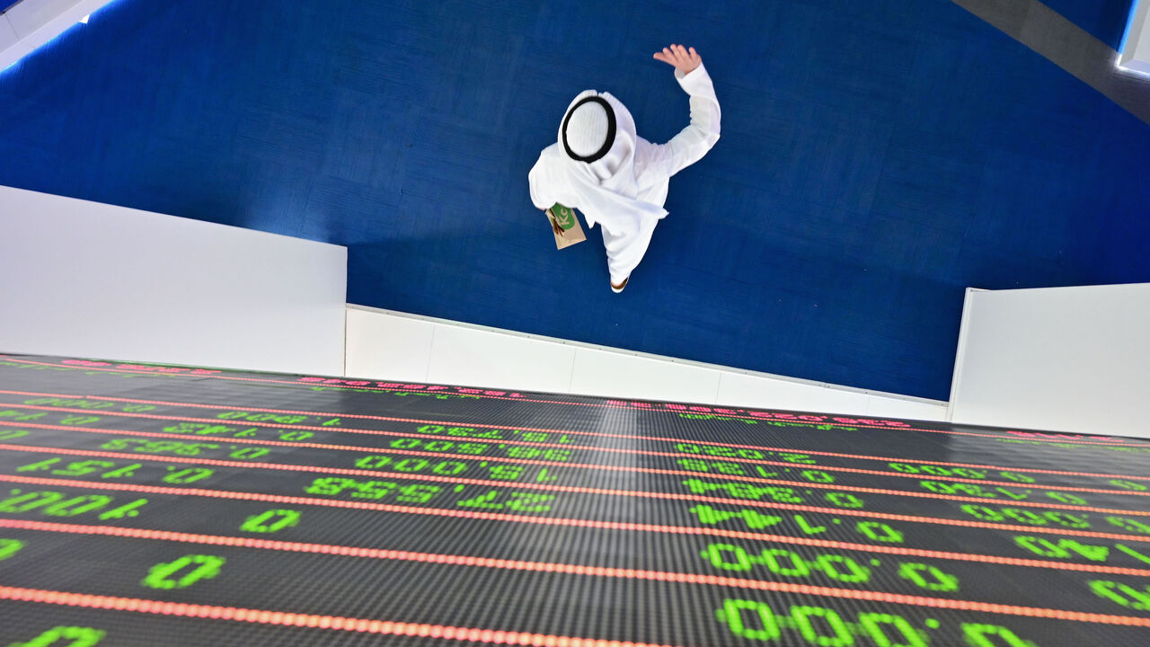 1205775088 TOPSHOT - A trader walks by beneath a stock display board at the Dubai Stock Exchange in the United Arab Emirates, on March 8, 2020. - Saudi's stock exchange fell 6.5 percent and other Gulf markets tumbled to multi-year lows at the start of trading after OPEC and its allies failed to clinch a deal over oil production cuts. (Photo by GIUSEPPE CACACE / AFP) (Photo by GIUSEPPE CACACE/AFP via Getty Images)