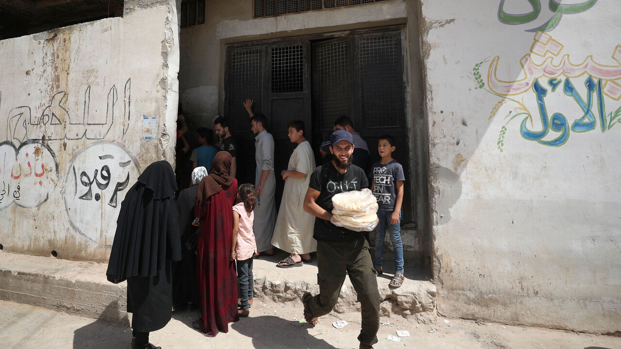 1219050523 Syrians buy bread in the town of Binnish in the country's northwestern Idlib province on June 9, 2020. - Syrians held a third day of rare anti-regime protests over deteriorating living conditions Tuesday in the government-held city of Sweida, a war monitor said, as the value of the pound sunk. The value of the Syrian pound has plummeted with dizzying speed in recent days on the informal market, sending prices skyrocketing nationwide and shuttering shops. Dozens rallied in the majority-Druze city of Sweida i