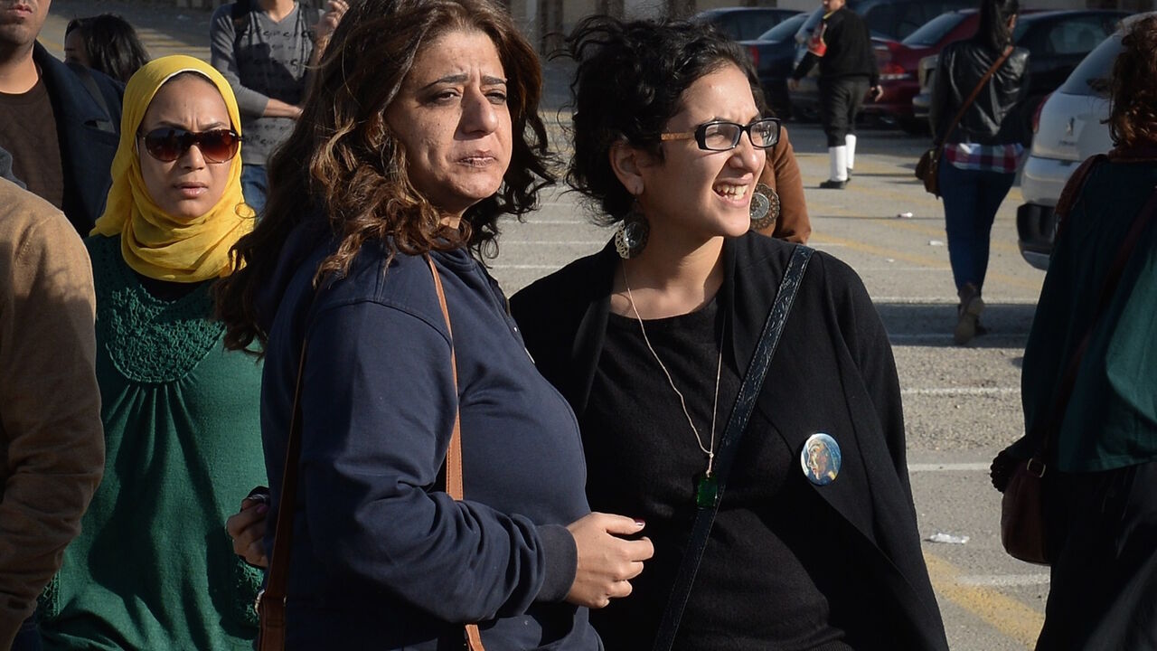 460868036 The sister (R) of Egyptian rights activist Sanaa Seif stands outside a court in Cairo on December 28, 2014, along with friends and relatives of the twenty-two other pro-democracy activists accused of holding an illegal protest last June, after an appeals court reduced the jail sentences from three years to two. The defendants were accused of holding an illegal protest on June 21 calling for the release of detainees and the annulment of a law that bans all but police-sanctioned demonstrations. They were also