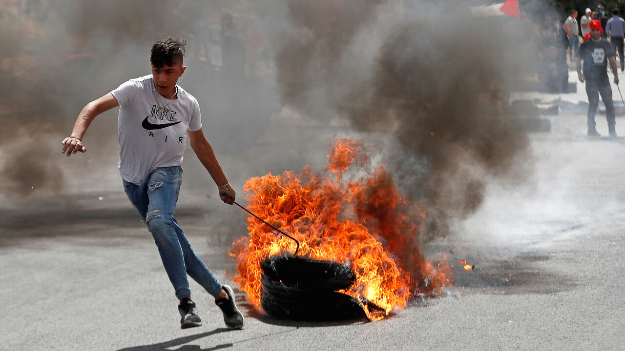 A Palestinian demonstrator pulls burning tires during a protest against Israel's plan to annex parts of the occupied West Bank, near the Jewish settlement of Beit El, near Ramallah June 19, 2020. REUTERS/Mohamad Torokman - RC2CCH92Y7IK