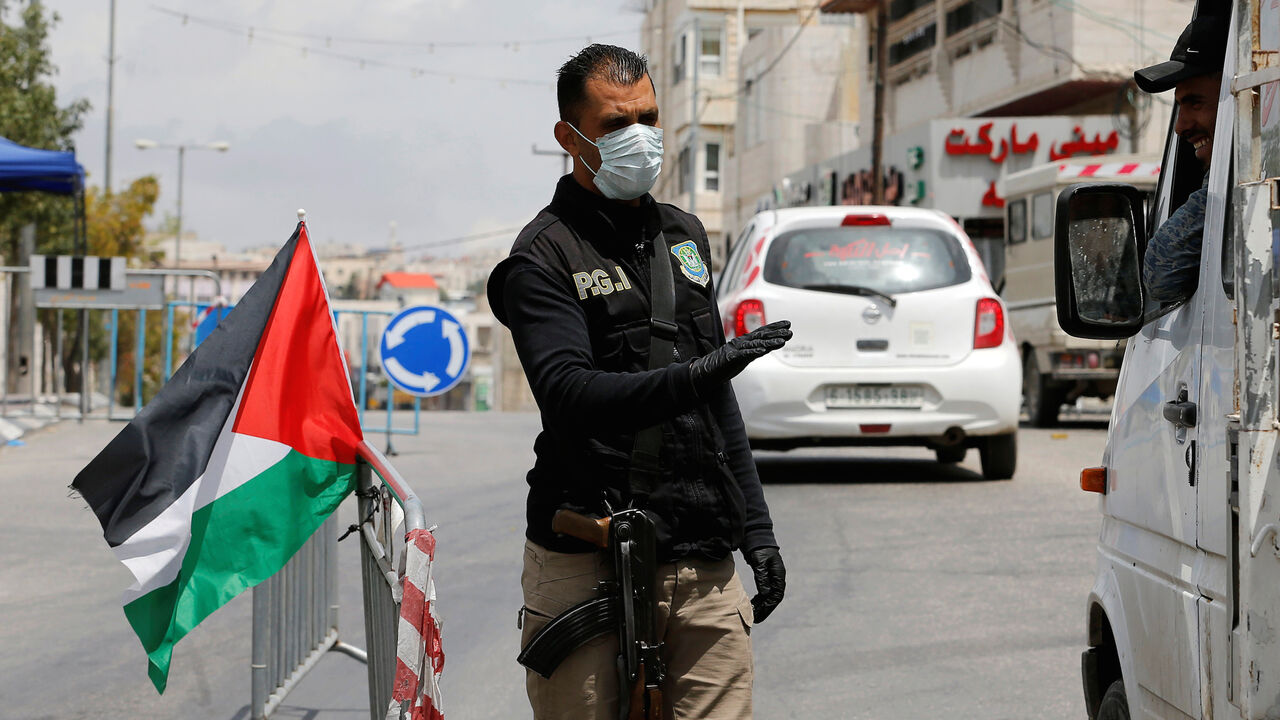 A member of Palestinian security forces gestures as he speaks with a truck occupant at a checkpoint after Palestinian President Mahmoud Abbas has extended to June 5 a state of emergency in response to the coronavirus crisis, in Hebron in the Israeli-occupied West Bank May 5, 2020. REUTERS/Mussa Qawasma - RC28IG9UZ9CC