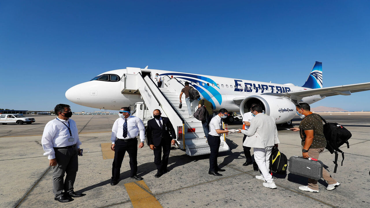 1221662454 Mask-clad EgyptAir crew (safety measure due to the COVID-19 coronavirus pandemic) check the documents of travellers preparing to board an Airbus A320neo aircraft on the tarmac at Sharm el-Sheikh International Airport, in the Red Sea resort city at the southern tip of the Sinai peninsula on June 20, 2020. (Photo by Khaled DESOUKI / AFP) (Photo by KHALED DESOUKI/AFP via Getty Images)