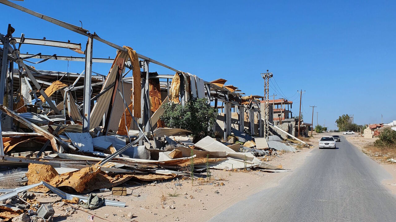 1221662808 A car advances past a damaged facility in the Salaheddin district south of the Libyan capital Tripoli, on June 21, 2020, as some residents return to the area after it has been demined. - Since 2015, a power struggle has pitted the Tripoli-based Government of National Accord (GNA) against strongman Khalifa Haftar, who claims legitimacy from an eastern-based elected parliament, and had been trying unsuccessfully to seize the capital since April 2019, until a pro-GNA counter-offensive at the beginning of June