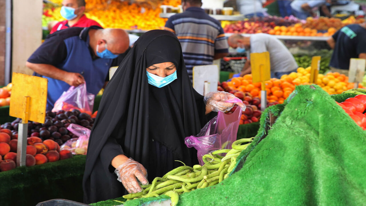 1227033509 An Iraqi woman wearing a protective mask amid the COVID-19 pandemic, buys fresh produce from a street seller at a market in Karrada, in the capital Baghdad, on July 14, 2020. - Iraq, in a bid to prevent the spread of the deadly COVID-19 illness, shut its 32 border crossings to goods and people coming from Iran, Turkey, Syria, Jordan and Saudi Arabia in mid-March, which helped its agriculture ministry accelerate a campaign to make Iraqi food markets self-sustainable, after years of relying on foreign imports