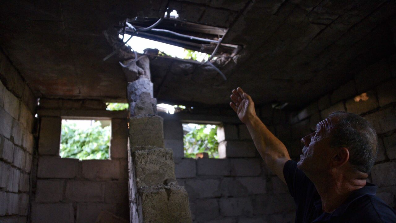 1227424250 Hrachik Pogosyan, 55, points at the roof of his house in the village of Aygepar in Tavush region damaged by recent shelling during armed clashes on the Armenian-Azerbaijani border on July 15, 2020. - Defence officials in Armenia and Azerbaijan said fighting on their border subsided on July 15, 2020 after several days of deadly clashes raised fears of a major flare-up. At least 16 people on both sides were killed in three days of shelling that started Sunday between the ex-Soviet republics, which have been l