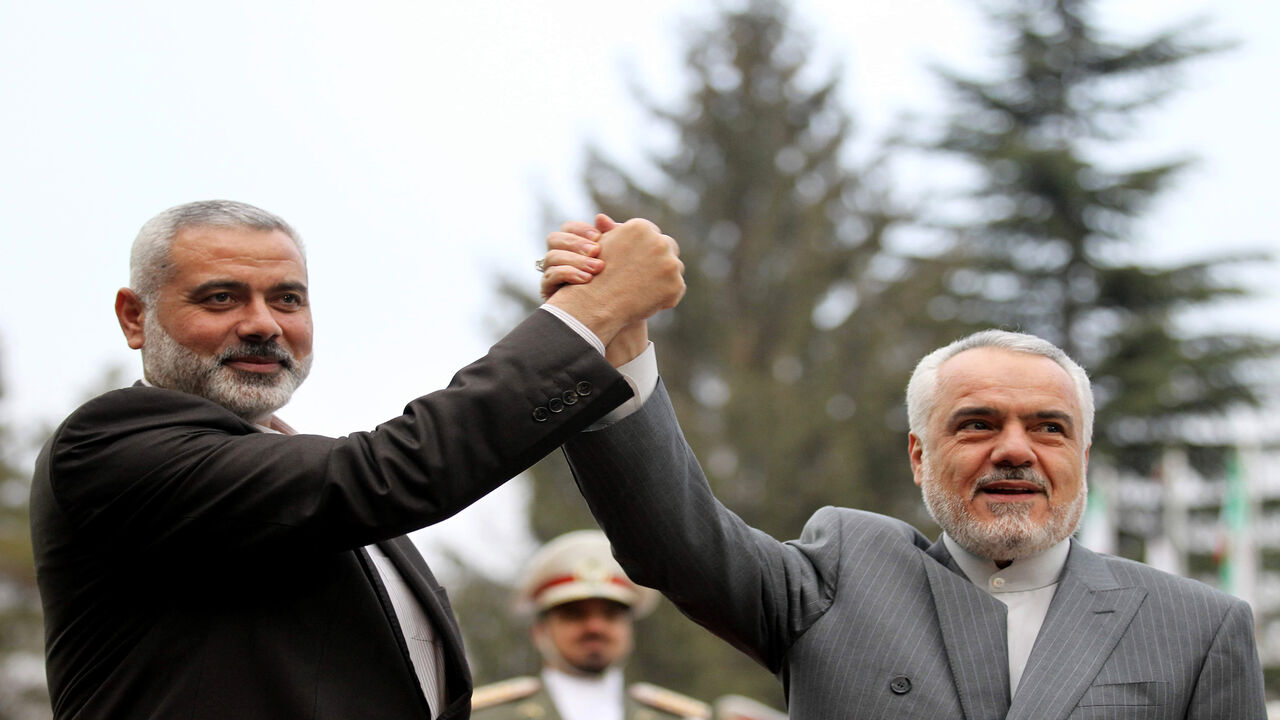 138666310 Iran's First Vice President Mohammad Reza Rahimi (R) and Ismail Haniya, Palestinian Hamas premier of Gaza, raise their hands upon the latter's arrival for a meeting in Tehran on February 10, 2012. AFP PHOTO/ATTA KENARE (Photo credit should read ATTA KENARE/AFP via Getty Images)