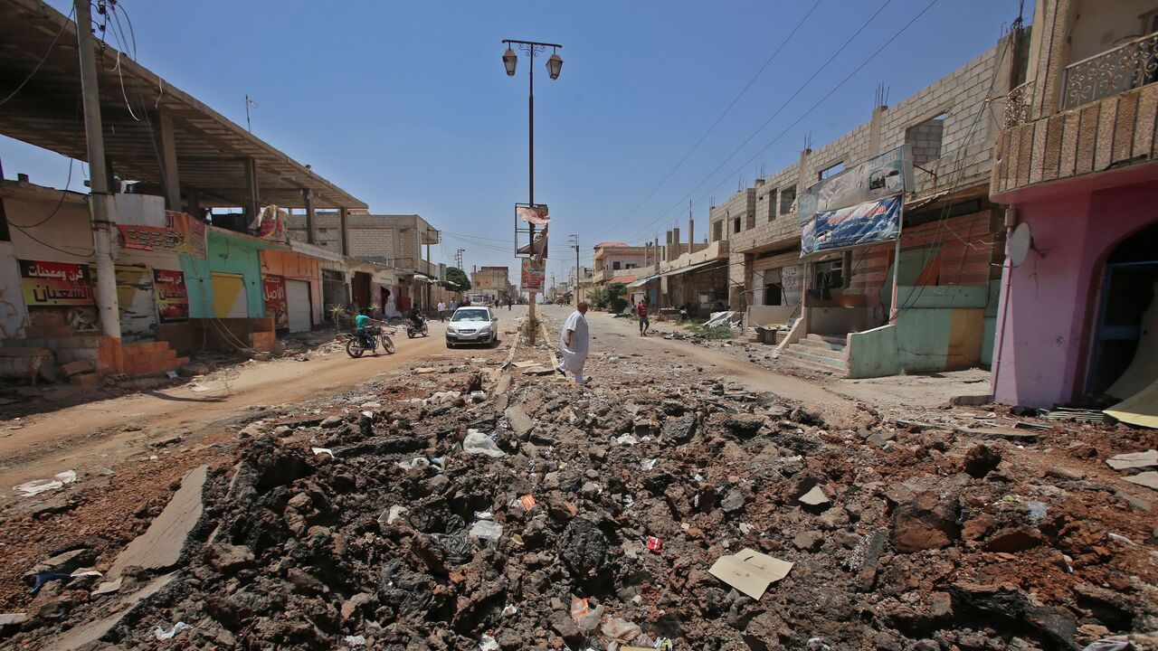 991479006 A Syrian civilian walks past a shell hole after Syrian government forces recently recaptured the village of Ghariyah ash Sharqiyah from the rebels, in the province of Daraa, on July 4, 2018. - Syrian rebels were facing a deadline Wednesday in negotiations with regime ally Russia to either agree to tough surrender terms in the south or come under a renewed military onslaught. (Photo by Youssef KARWASHAN / AFP) (Photo credit should read YOUSSEF KARWASHAN/AFP via Getty Images)