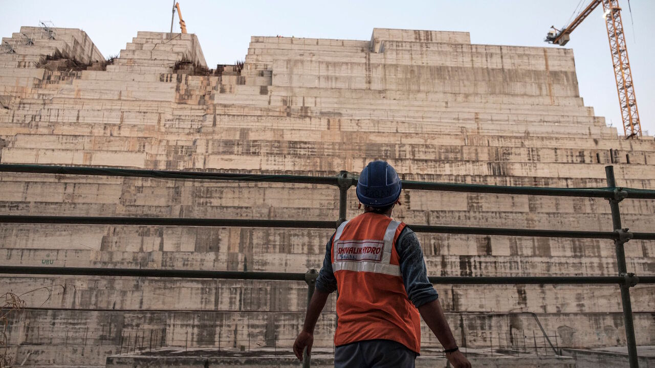 1192325388 A construction worker looks at the Grand Ethiopian Renaissance Dam (GERD), near Guba in Ethiopia, on December 26, 2019. - The Grand Ethiopian Renaissance Dam, a 145-metre-high, 1.8-kilometre-long concrete colossus is set to become the largest hydropower plant in Africa.
Across Ethiopia, poor farmers and rich businessmen alike eagerly await the more than 6,000 megawatts of electricity officials say it will ultimately provide.
Yet as thousands of workers toil day and night to finish the project, Ethiopian ne