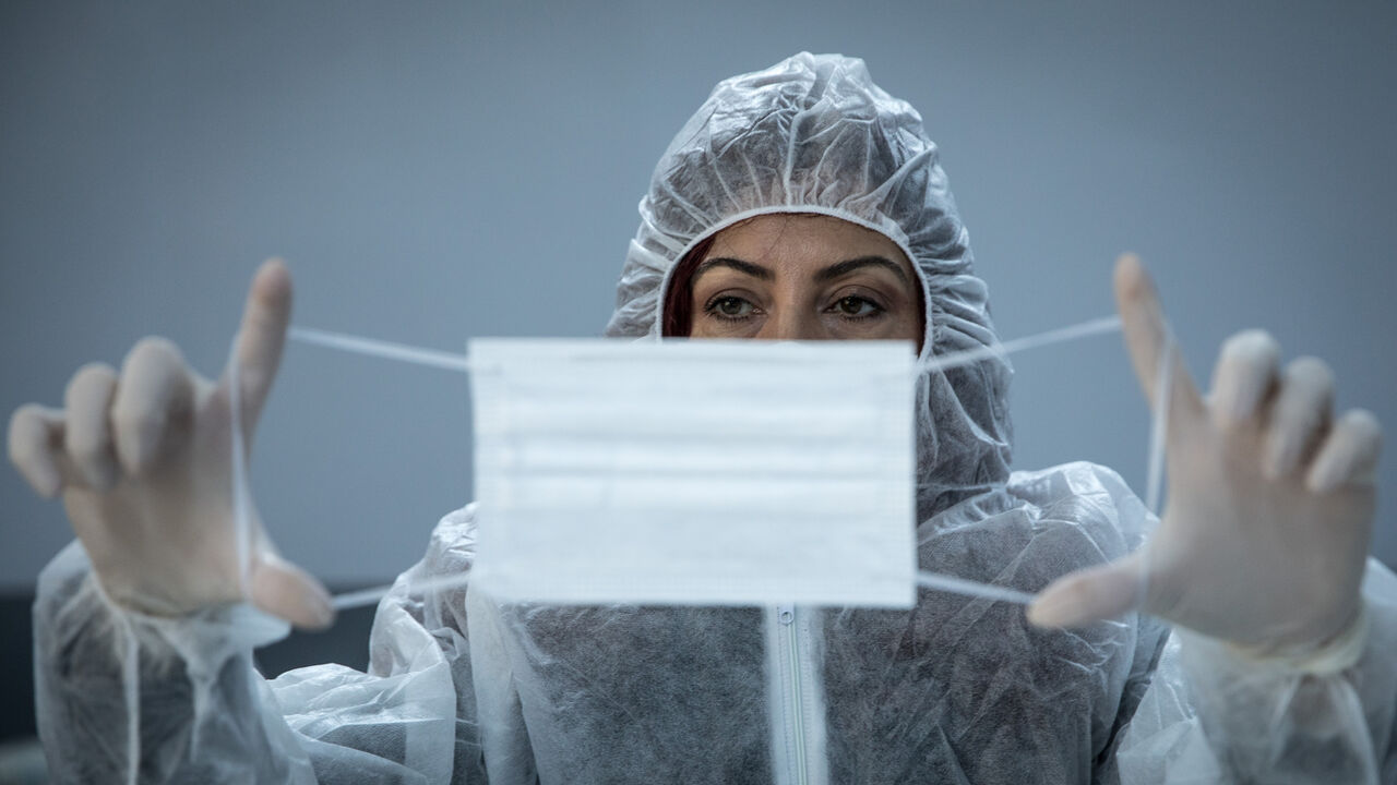1217204898 ISTANBUL, TURKEY - APRIL 06: A teacher inspects a newly made surgical face mask amid the COVID-19 outbreak at a Vocational and Technical Anatolian School on April 06, 2020 in Istanbul, Turkey. Since the outbreak of the Coronavirus Turkey's Ministry of National Education Istanbul Province Directorate, has launched a school program, turning some schools into makeshift factories to produce medical equipment. The program that is run and operated by the schools teachers themselves, has produced 2,700,000 surgic