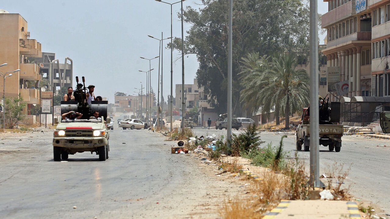 1217497187 Fighters loyal to the UN-recognised Libyan Government of National Accord (GNA) ride in a technical (pickup truck mounted with turret) along a road in the Qasr bin Ghashir district south of the Libyan capital Tripoli on June 4, 2020, after the area was taken over by pro-GNA forces following clashes with rival forces loyal to strongman Khalifa Haftar. - The GNA said on June 4 that it was back in full control of the capital and its suburbs after more than a year of fighting off an offensive by eastern strongma