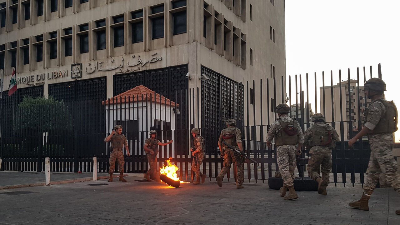 1219321448 Lebanese Army soldiers roll away a flaming tire from the fence surrounding the local branch of the Banque du Liban (Lebanese Central Bank) as protesters gather to demonstrate against dire economic conditions in the northern city of Tripoli on June 11, 2020. - The Lebanese pound sank to a record low on the black market on June 11 despite the authorities' attempts to halt the plunge of the crisis-hit country's currency, money changers said. Lebanon is in the grips of its worst economic turmoil in decades, and