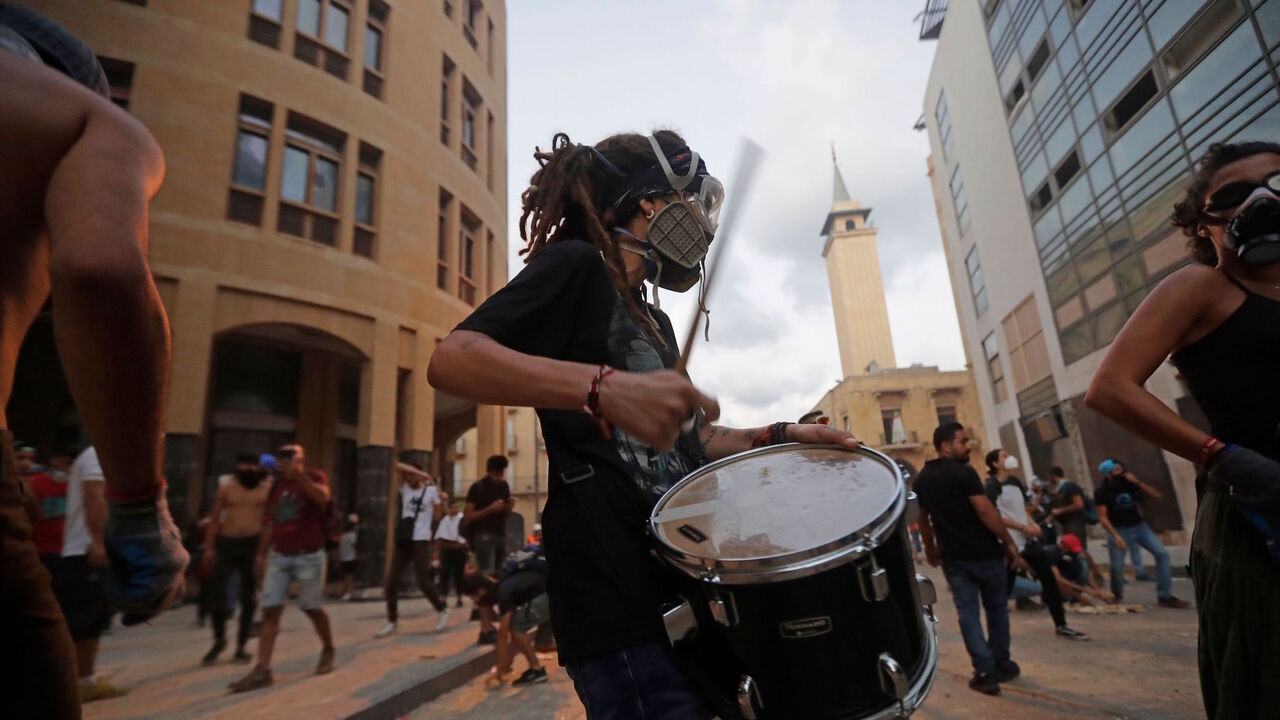 1227979207 TOPSHOT - A Lebanese protester beats a drum amid clashes with security forces near an access street to the parliament in central Beirut on August 9, 2020, following a deadly explosion that turned the city into a disaster zone. - The huge chemical explosion that hit Beirut's port, devastating large parts of the Lebanese capital and claiming over 150 lives, left a 43-metre (141 foot) deep crater, a security official said. (Photo by JOSEPH EID / AFP) (Photo by JOSEPH EID/AFP via Getty Images)