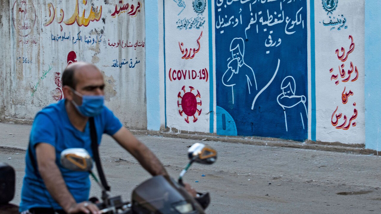 1228071098 A Syrian man rides a motorbike past a mural painted as part of an awareness campaign by the United Nations International Children's Emergency Fund (UNICEF) and World Health Organization (WHO) intitative, bearing instructions on protection from COVID-19 in the Kurdish-majority city of Qamishli of Syria's northeastern Hasakeh province on August 16, 2020, after a spike in infections in the area. (Photo by Delil SOULEIMAN / AFP) (Photo by DELIL SOULEIMAN/AFP via Getty Images)