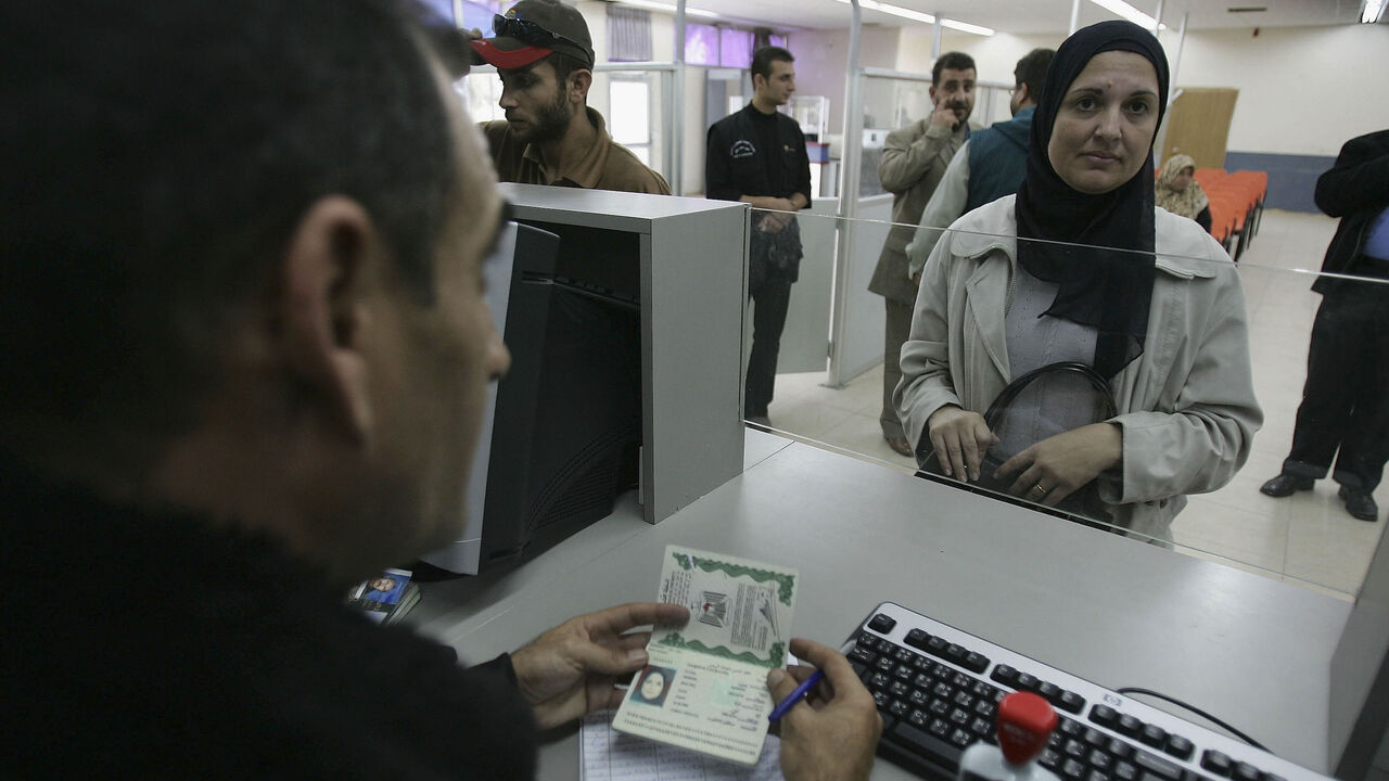 56177569 RAFAH, GAZA STRIP NOVEMBER 15: A Palestinian security man checks a passport of a traveller as she comes back from Egypt November 15, 2005 at the border crossing of Rafah in the southern Gaza Strip. Palestinian and Egyptian security officials opened the Rafah border as an exception for travel in coordination with the Israeli Army. Palestinians and Israel have reached an agreement today under strong U.S. pressure to open borders of Gaza starting November 25, 2005 as an attempt to turn the economically cripple