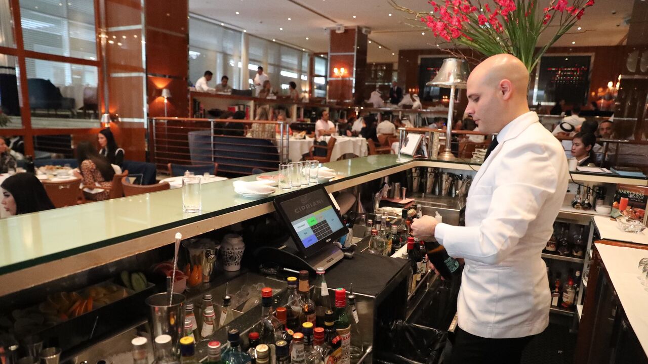 1056294626 A bar tendant serves customers at a restaurant in Dubai on August 30, 2018. - As temperature levels soar in Dubai, residents and tourists in the rich Emirate turn to a much favourite indoor outing during summer days: restaurants. From business lunches, to fresh decorations, Dubais top restaurants compete to attract those costumers looking to beat the heat with a customised cool drink, or an award winning plate. (Photo by KARIM SAHIB / AFP) (Photo credit should read KARIM SAHIB/AFP via Getty Images)