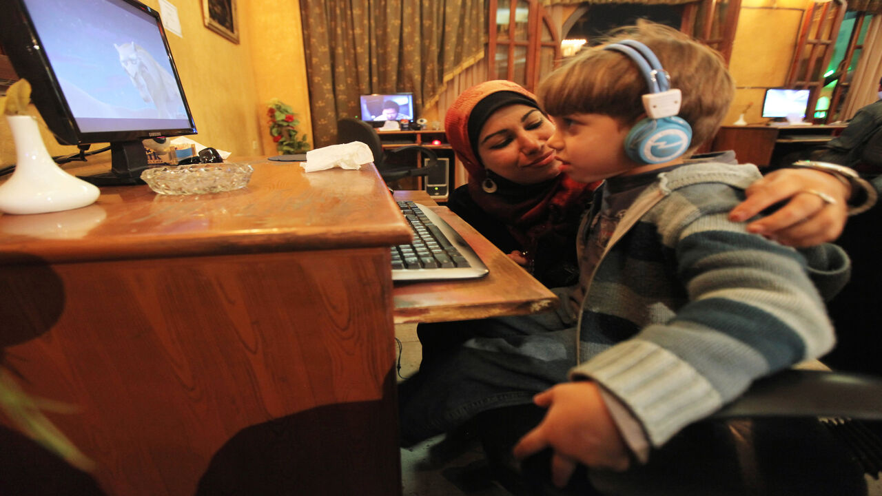 108095977 TO GO WITH AFP STORY BY INES BEL AIBAEgyptian radio presenter and divorcee Mahassen Saber takes a break from working on her Internet-based radio station "Divorcees Radio" to check on her son as he watches a film at an Internet cafe in Zagazig, 90 kms north of Cairo, on January 14, 2010. When Mahassen Saber divorced her husband after four years of difficult procedures, she did not expect to become the centre of gossip. To fight the prejudice, the young Egyptian decided to launch "Divorcees Radio". AFP PHOTO/