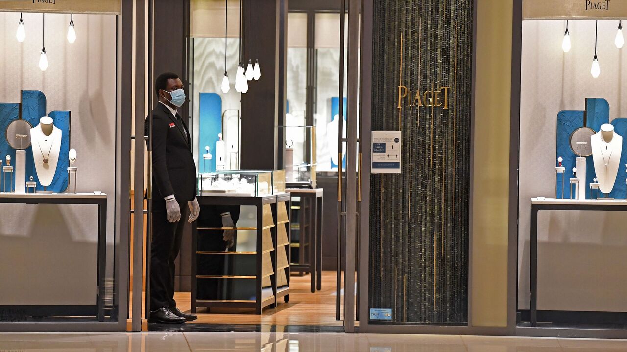 1211222607 A security guard, wearing protective masks to combat the spread coronavirus, stands guard outside a store in the Mall of Dubai on April 28, 2020, after the mall was reopened. (Photo by Karim SAHIB / AFP) (Photo by KARIM SAHIB/AFP via Getty Images)