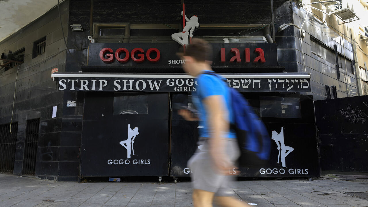 1211647616 A boy walks past the closed Gogo Girls strip club in the Israeli city of Tel Aviv on March 5, 2020. - The demise of Tel Aviv's strip clubs was accelerated in 2018, when Israel's parliament, the Knesset, passed a law banning brothels. But the final straw came in April last year when the public prosecutor issued a directive to clamp down on lap dances, arguing they could in some cases be viewed as prostitution. (Photo by Emmanuel DUNAND / AFP) (Photo by EMMANUEL DUNAND/AFP via Getty Images)